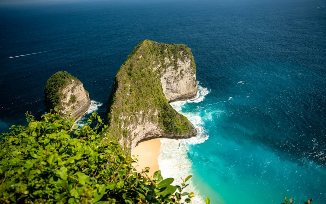 Dramatic cliffs overlook a tropical beach with turquoise water.