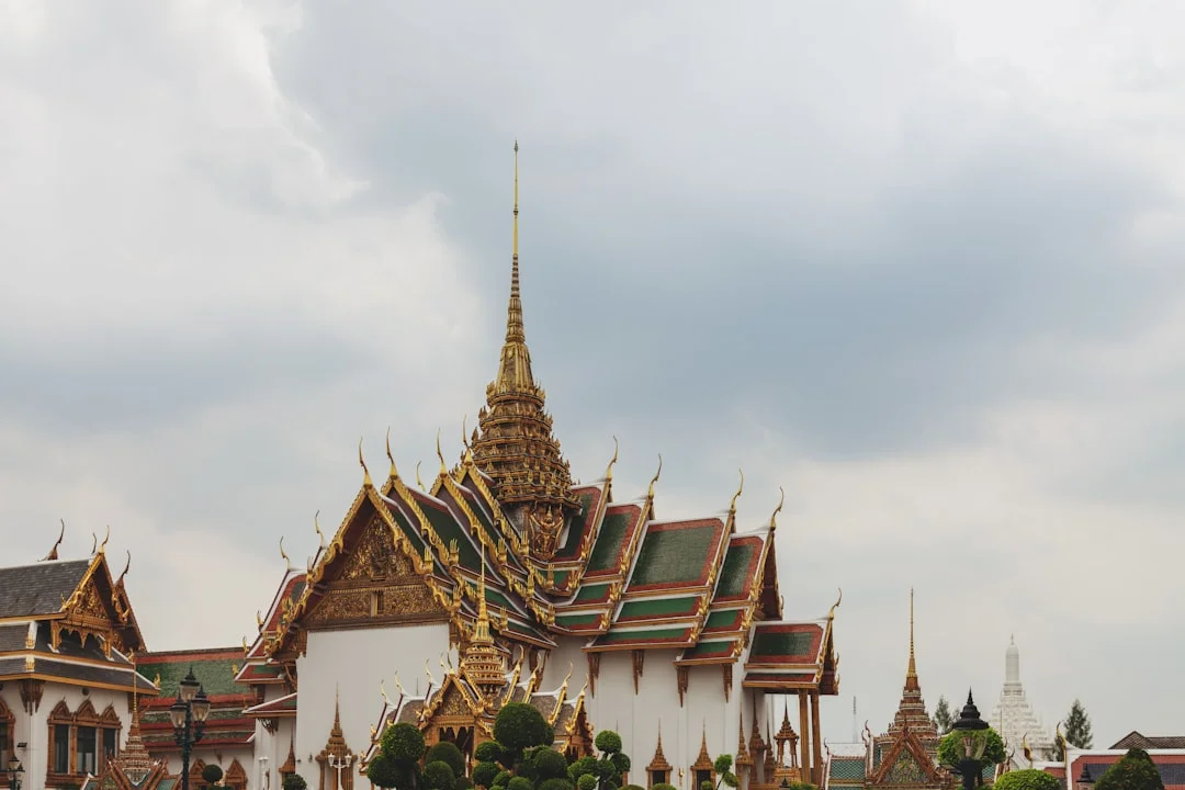 Ornate temple architecture with golden spires under cloudy sky
