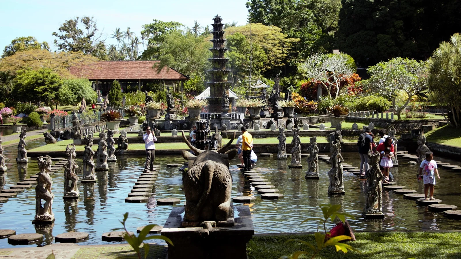 a group of people standing around a fountain with statues in it